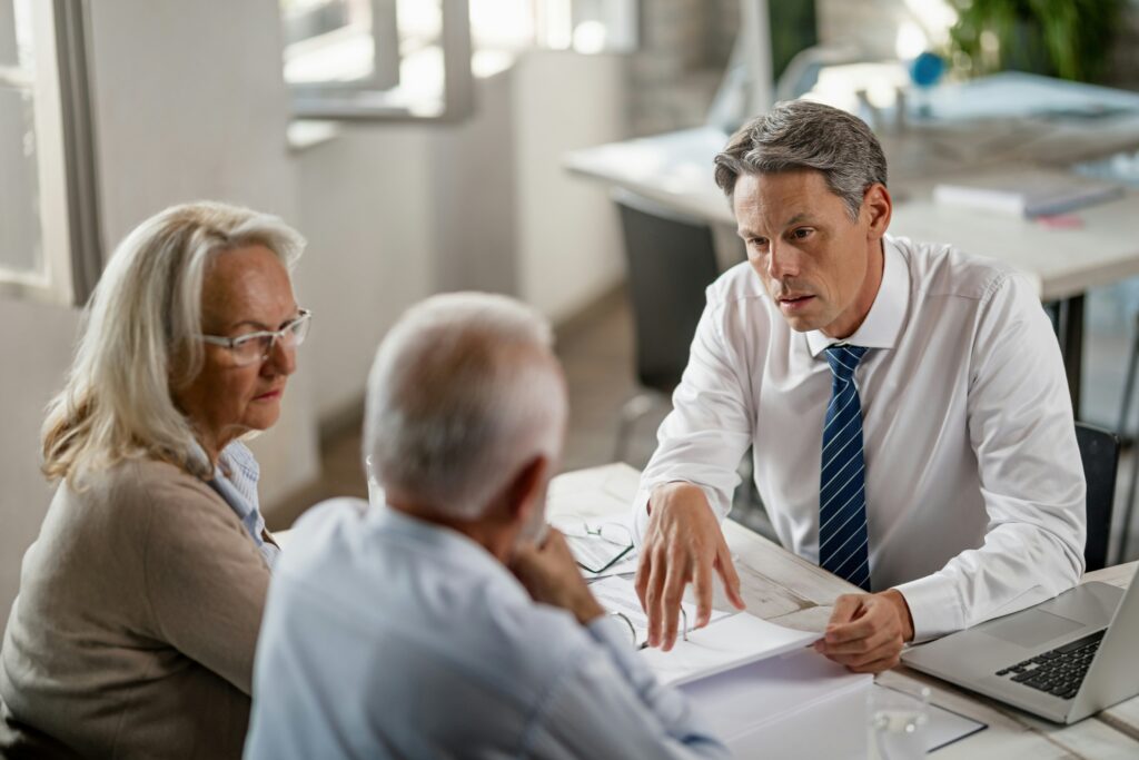 A man and woman engage in conversation with an older couple, sharing smiles and attentive expressions.