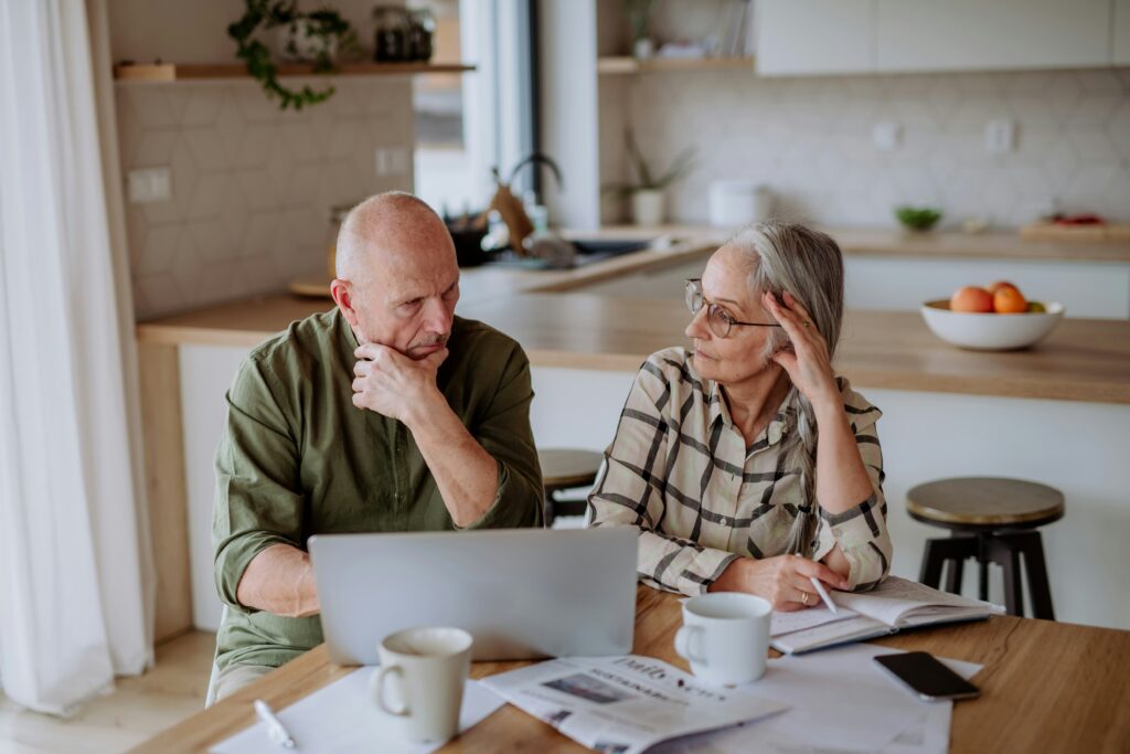 An older couple sits at a table, focused on a laptop, sharing a moment of connection and engagement.